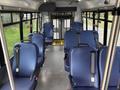 Interior view of a 2021 Ford Transit-350 with blue cloth seats arranged in a passenger configuration and a rear wheelchair lift visible in the background