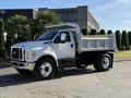A 2017 Ford F-650 Super Duty truck with a flatbed design featuring a white exterior and large wheels parked in a lot