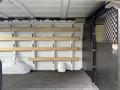 Interior of a 2023 GMC Savana cargo van featuring wooden shelves along the walls and a partition for driver safety