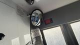 A 2021 Ford Transit interior featuring a circular side mirror with a warning label and a control panel next to it