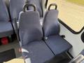 A pair of blue fabric seats in a 2017 Chevrolet Express with seatbelt buckles and hand grips attached to the backrests