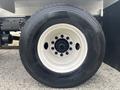 A close-up of a 2006 Freightliner M2 106 truck tire featuring a white rim and black tread with visible brand markings and a six-bolt wheel hub