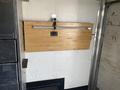 A foldable wooden workbench mounted on a wall with a metal support system attached to a trailer interior