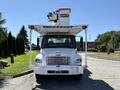 A 2010 Freightliner M2 106 bucket truck with a mounted aerial lift above the cab and a large front grille
