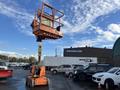A 2012 JLG E400AJFN aerial lift with a raised platform and orange color standing on a paved surface