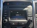 A car radio display with a digital screen showing the time as 4:00 and a radio station set to 102.7 with controls for volume and settings visible