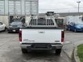 A white 2012 GMC Canyon pickup truck with a black bed liner and a ladder rack installed on the bed
