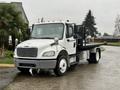 A 2019 Freightliner M2 truck in white with a flatbed and chrome accents sits in a parking area with a palm tree nearby