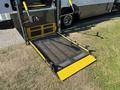A yellow and black wheelchair ramp extending from the back of a 2020 Chevrolet Express van with a textured surface for traction and handrails on the sides