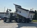 A 2013 International WorkStar dump truck with an elevated dump bed and a white and black color scheme showcasing its wheels and chassis