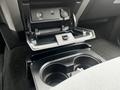 A black plastic cup holder and storage compartment located in the center console of a 2014 Ford F-150 with a USB port and audio input visible