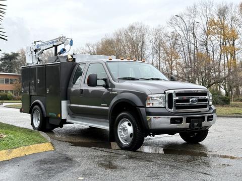 A gray 2006 Ford F-450 Super Duty truck with a utility body featuring equipment on top and side compartments