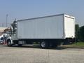A white 2012 Hino 338 box truck with a tall cargo area and dual rear wheels parked on a pavement