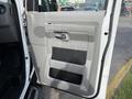 The interior door panel of a 2013 Ford Econoline featuring a gray speaker grille and a handle with a storage compartment below