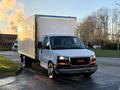 A 2015 GMC Savana cargo van with a white box truck body parked at an angle facing forward