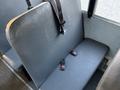 A black upholstered bench seat with two red seatbelt clips on a school bus