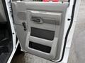 The image shows the open driver's side door of a 2022 Ford E-450 featuring a gray interior door panel with a handle and a storage compartment