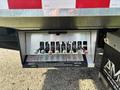 A metal panel with multiple levers and warning labels attached to the rear of a 2022 Freightliner M2 106 truck