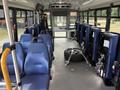 Interior of a 2020 Chevrolet Express with blue seating on one side and secured equipment including a spare tire on the floor