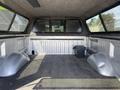 A 2014 Ford F-150 with a covered truck bed featuring a gray carpet liner and a small black toolbox on the floor