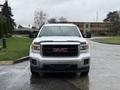 A 2015 GMC Sierra 1500 front view with a silver body and black grille featuring the GMC logo prominently displayed