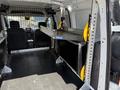 Interior of a 2021 Ford Transit Connect showing a metal frame with yellow support arms secured against a black panel with a protective mesh barrier in the background