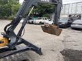 A 2017 John Deere 50G excavator with a metal bucket raised in the air ready for digging or transporting materials