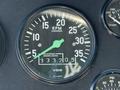 A black dashboard gauge displaying an RPM reading with a green needle pointing to 15 and an odometer showing 333205 engine hours