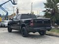 A black 2021 RAM 1500 pickup truck seen from the rear with a high stance and blacked-out wheels