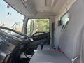 Interior of a 2012 Hino 338 truck featuring a driver's seat and passenger seat with gray upholstery and a dashboard with controls and gear shift visible