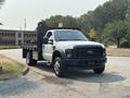 2009 Ford F-450 Super Duty truck with a flatbed and a crane attachment on the rear in white color