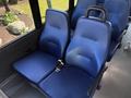 Two blue upholstered seats with a seatbelt in a vehicle interior