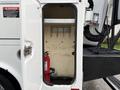 A 2008 Ford F-550 service truck with an open side compartment featuring a fire extinguisher and storage hooks on the wall