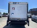 A 2014 International TerraStar box truck seen from the rear with a white and blue back panel featuring faded patches and a license plate at the top