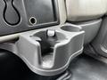A gray cup holder attached to the interior of a 2011 International 4400 truck's dashboard with a circular design and a slot for a drink container