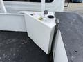 A white fuel tank mounted on a flatbed truck with a circular cap and a hose attached to the side