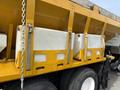 A yellow 2016 International 7600 truck with a large dump bed featuring white storage tanks mounted on the side