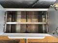 An empty silver metal cargo storage compartment with two horizontal dividers and hinges on both sides