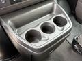 A black plastic cup holder with three openings designed to hold drinks in a vehicle's interior