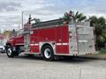A red 2002 GMC C7500 fire truck with a metal ladder system and various firefighting equipment on the side