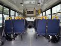 Interior view of a 2015 Chevrolet Express shuttle bus showing rows of navy blue seats with yellow headrests and safety belts