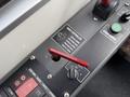 A close-up view of a bus control panel featuring a red door controller lever a green start engine button and various switches and indicators
