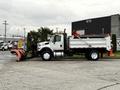A 2012 International 7400 truck with a snow plow attachment is parked, featuring a white body and orange accents, ready for winter operations