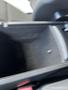 A 2015 Jeep Grand Cherokee interior featuring a black center console with an open compartment and a small item inside