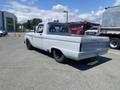 A classic 1962 Ford 2WHDR pickup truck in light gray with a vintage design and black wheels, viewed from the rear at an angle