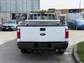 A white 2011 Ford F-350 Super Duty truck viewed from the rear with a metal rack in the truck bed
