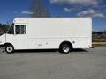 A white 2012 Ford Econoline delivery truck with a boxy design and side doors parked on a gravel surface
