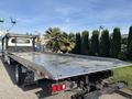2022 Freightliner M2 106 flatbed truck with a metallic flatbed and retractable hitch visible in the foreground