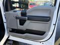 Interior door panel of a 2020 Ford F-350 featuring textured gray plastic and a black handle with storage compartments