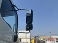 A 2012 Hino 338 truck with a large side mirror reflecting the surrounding area